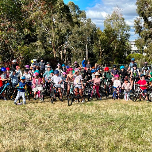 A large group of people standing together in a feild with their bicycles - opens in a new tab